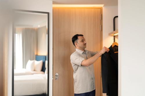 a man is trying on a suit in a hotel room at Hilton Garden Inn Mumbai International Airport in Mumbai