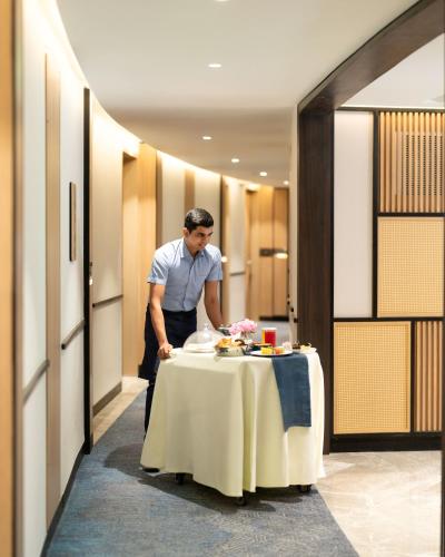 a man standing next to a table with food on it at Hilton Garden Inn Mumbai International Airport in Mumbai