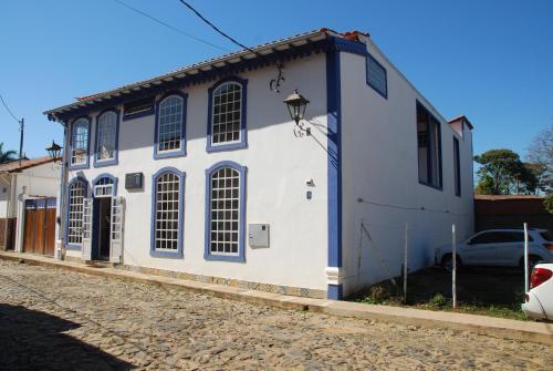 a white house with blue trim on a street at Pousada Solar Das Gerais in Tiradentes