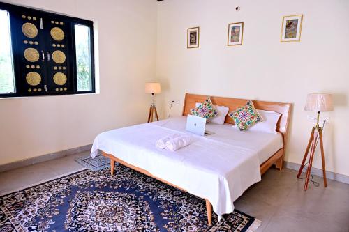a bedroom with a bed with a laptop on it at Jaipur Eco Village in Jaipur