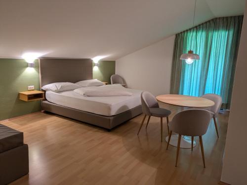 a bedroom with a bed and a table and chairs at Garni Saltneregg Ferienwohnungen in Caldaro