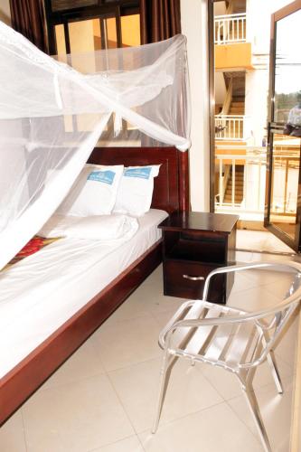 a bed and a chair in a room with a window at Okura Hotel in Gulu
