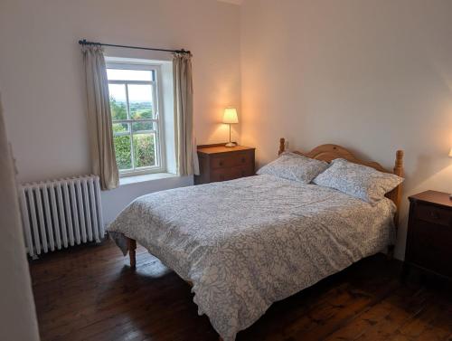 a bedroom with a bed and a window at Charming 2 bedroom Cottage near Skibbereen with stove and views 