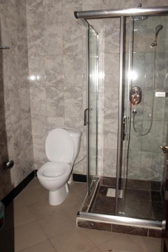 a bathroom with a toilet and a glass shower at Okura Hotel in Gulu