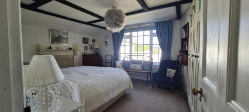 a bedroom with a bed and a chair and a window at Charming cottage in Pilton-newly renovated in Barnstaple