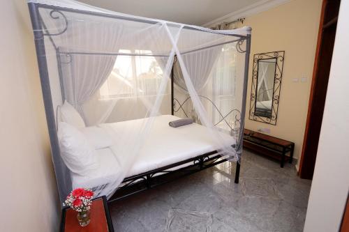 a bedroom with a canopy bed with white sheets at Bon Bini Residence in Kampala