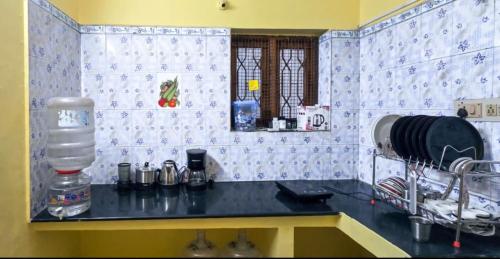 a kitchen with a black counter top and blue and white tiles at Hostel Madras in Chennai