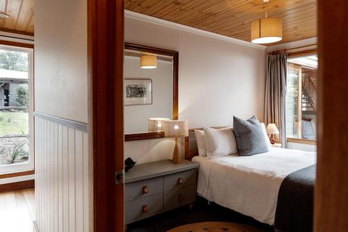 a bedroom with a bed and a mirror and a window at Mandala Bruny Island in Alonnah