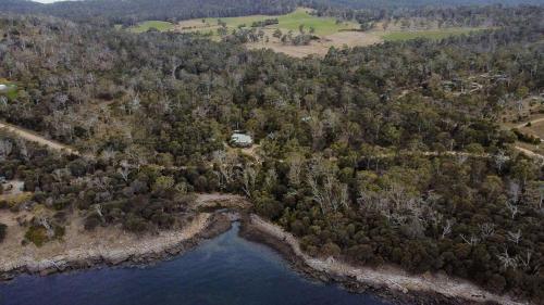 an aerial view of a lake with trees and a house at Mandala Bruny Island in Alonnah