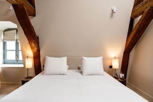 a bedroom with a large white bed with two lamps at Hôtel Royal Beaulaincourt in Béthune