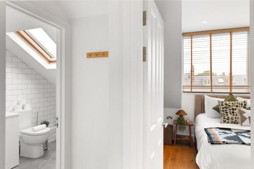 1 dormitorio con cama, aseo y ventana en Sunny TopFloor 1BR , Balcony Views Sleeps 3, en Londres