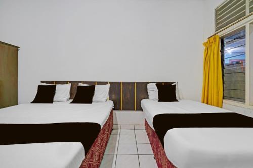 two beds in a room with a window at OYO 94802 Hotel Prima in Tjiandjur