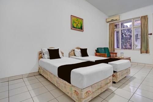 a bedroom with two beds and a window at OYO 94802 Hotel Prima in Tjiandjur