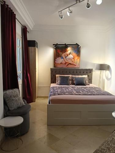 a bedroom with a bed and a painting on the wall at Appartement Yasmine Hammamet in Yasmine