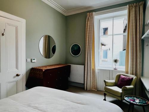 a bedroom with a bed and a chair and a mirror at Dungora House in Crieff
