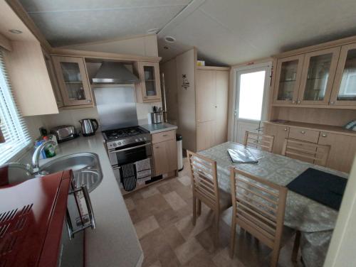 a kitchen with a table and chairs and a sink at Sea Shore Chalet - Rockley Park in Lytchett Minster