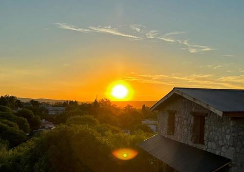 una puesta de sol desde un edificio con el sol en el cielo en La Claudina - Cabañas Boutique en las Sierras, en Capilla del Monte