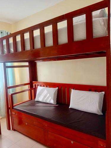 a wooden bunk bed with two white pillows on it at DaLei 2-330 Sleeps 8pax at Marina Spatial Condominium in Dumaguete City in Dumaguete