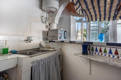 eine Küche mit Spüle und Mikrowelle in der Unterkunft Chiclana Boutique Oasis del Mar in Chiclana de la Frontera
