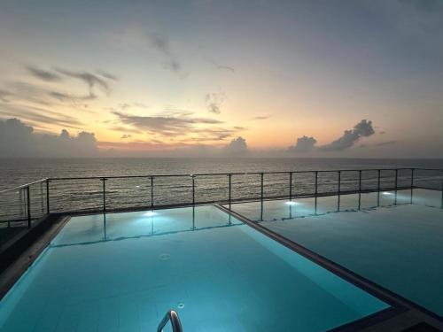 a swimming pool with the ocean in the background at The Bay in Dehiwala