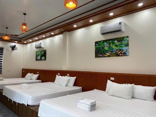 a room with two beds and a tv on the wall at Ninh Binh Royal Homestay in Ninh Binh