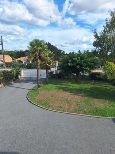 a driveway with two palm trees in a yard at Villa du Rosais in Talmont-Saint-Hilaire