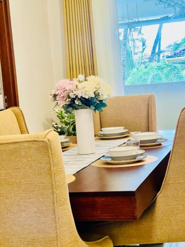 a dining room table with a vase of flowers on it at The Bay in Dehiwala