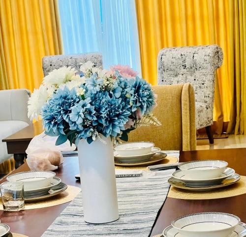 a white vase with blue flowers on a table at The Bay in Dehiwala