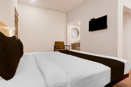a bedroom with a white bed and a television at Townhouse Nagpur Junction Formerly Hotel Woodland in Nagpur