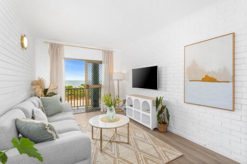 a living room with a couch and a tv at Sunrise Beachfront Getaway in Yeppoon
