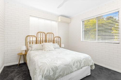 a white bedroom with a bed and a window at Sunrise Beachfront Getaway in Yeppoon