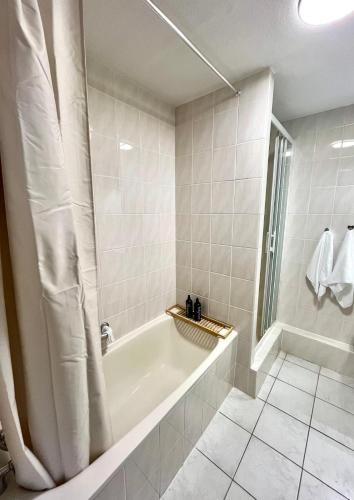 a white bathroom with a tub and a window at Appartement Cosy & Spacieux - Centre ville in Strasbourg