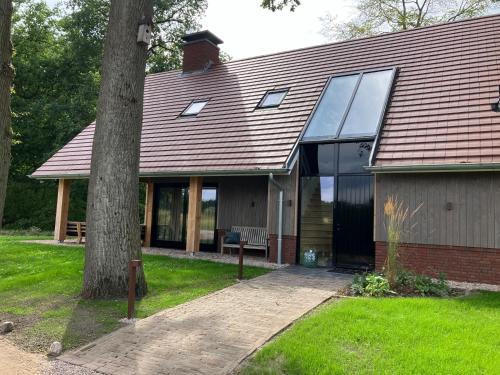 a house with a large window and a tree at Bos appartement voor 4 personen in De Lutte