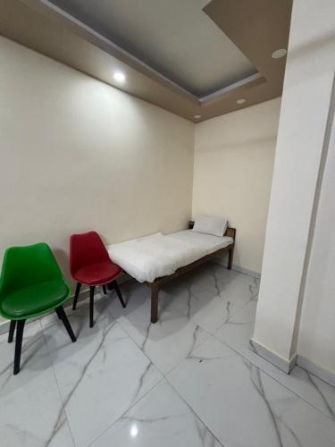 a room with a bed and two green chairs at Kerala Homes Near Nizamuddin in New Delhi