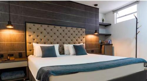 a bedroom with a large bed with a large headboard at Hotel California Medellin in Medellín