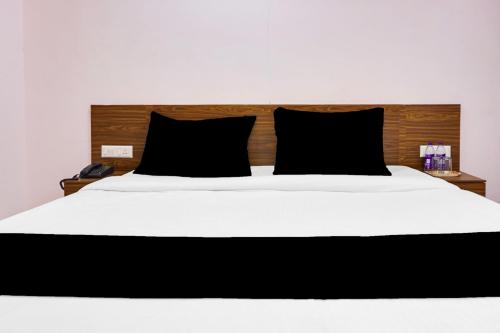 a bedroom with a large white bed with black pillows at Super Collection O Chandan Nagar Kharadi Formerly Kharadi INN in Pune