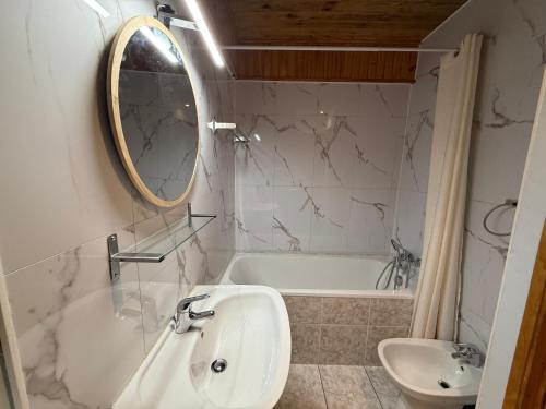 a bathroom with a sink and a tub and a mirror at Chalet Le refuge in Allos