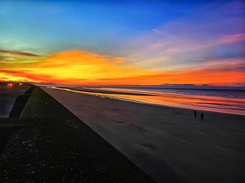 a sunset on a beach with the ocean at The Hideaway in Great Meols