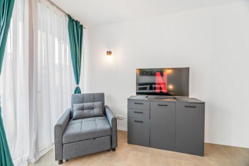 a living room with a chair and a tv on a dresser at Bodensee Penthouse 23i - Seesicht - Billiard - Panorama Exklusive in Öhningen