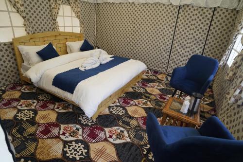 a bedroom with a bed and two blue chairs at Parvati Baag Camps by Feast Holidays in Saturang