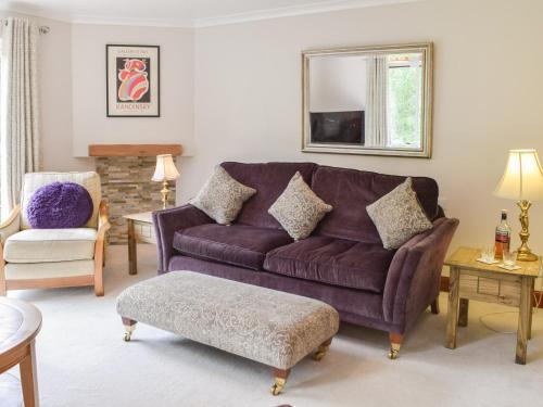 ein Wohnzimmer mit einem lila Sofa und einem Stuhl in der Unterkunft Tamarchan Lodge in Ballachulish