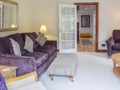 ein Wohnzimmer mit einem lila Sofa und einem Tisch in der Unterkunft Tamarchan Lodge in Ballachulish
