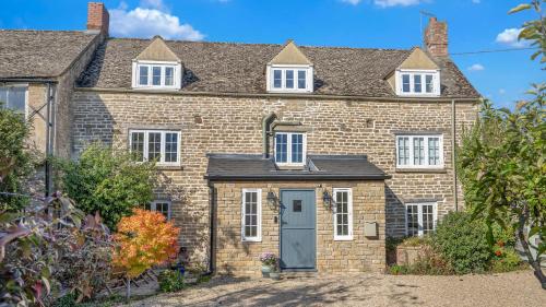 an old brick house with a blue door at Taylor's Cottage in Alvescot