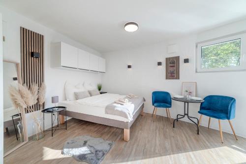 a white bedroom with a bed and two blue chairs at SpaceStays Bunker Messe Apartment Wi-Fi TV in Essen