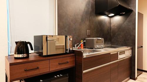 a kitchen with a sink and a microwave at HOTELHOUSE Nekogoya Shindohigashi 新道東 in Sapporo