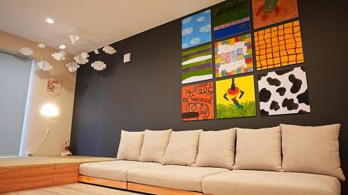 a couch in a room with paintings on the wall at HOTELHOUSE Nekogoya Shindohigashi 新道東 in Sapporo