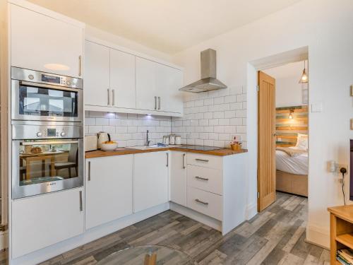 a kitchen with white cabinets and stainless steel appliances at Driftwood - Uk34192 in Goodrington