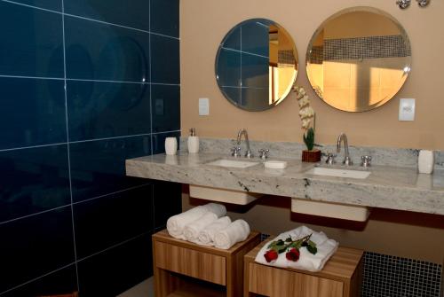 a bathroom with two sinks and two mirrors at Ramada by Wyndham Furnaspark in Formiga