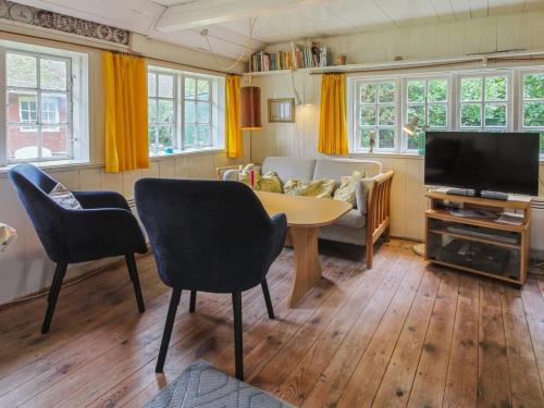 a living room with a tv and a table and chairs at Holiday Home Thorfrid - 1km from the sea by Interhome in Sønderho