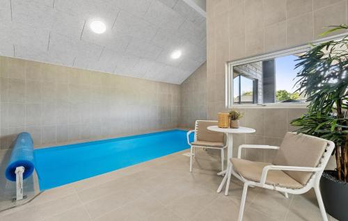 a swimming pool in a room with a table and chairs at Awesome Home In Nørre Nebel With Sauna in Nørre Nebel